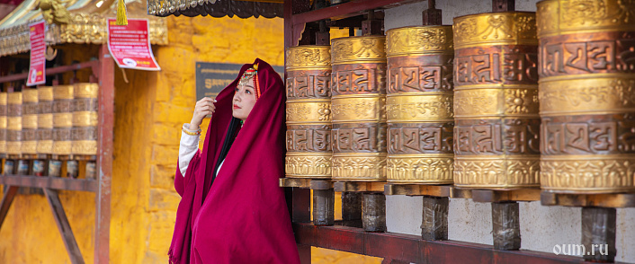 тибетская девушка у молитвенных барабанов фото