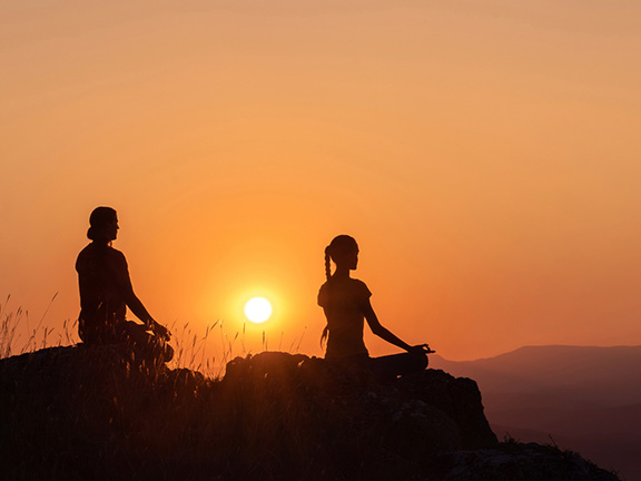 мужчина и женщина медитируют, закат