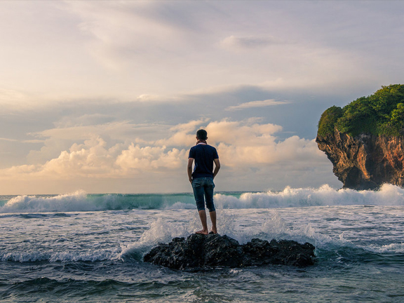 мужчина стоит на камне у моря