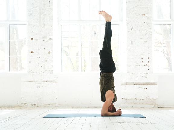 мужчина стоит в ширшасане