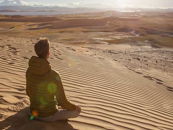 парень медитирует на дюнах