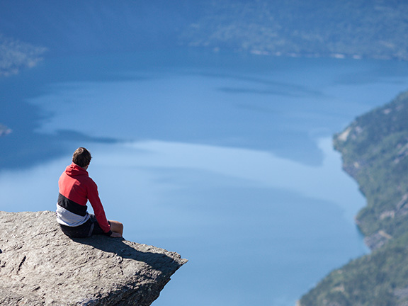 парень сидит на краю скалы