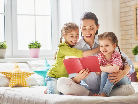 мама читает книгу с дочками