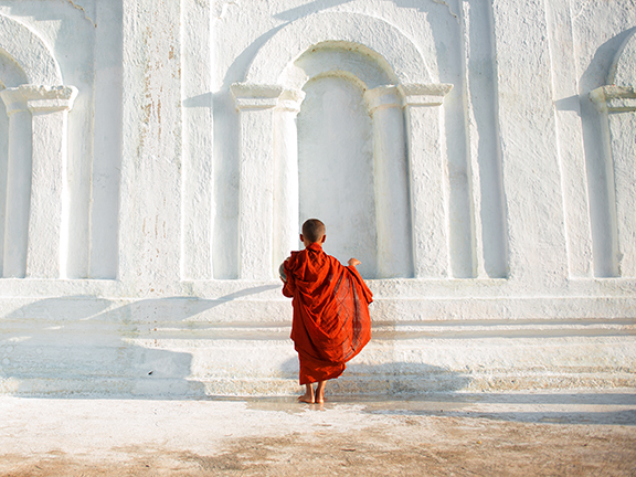 мальчик монах на фоне белой стены