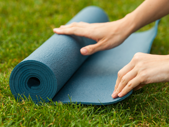 девушка раскатывает коврик для йоги фото