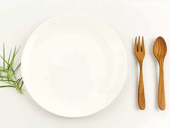 пустая тарелка, деревянные ложка и вилка