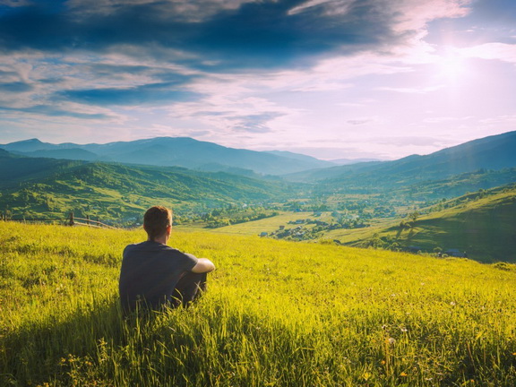 парень сидит на холме