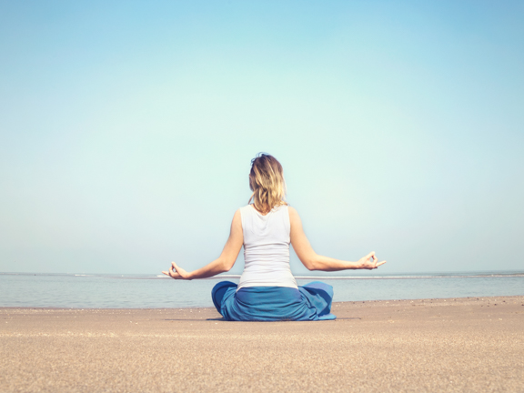 девушка медитирует на берегу моря
