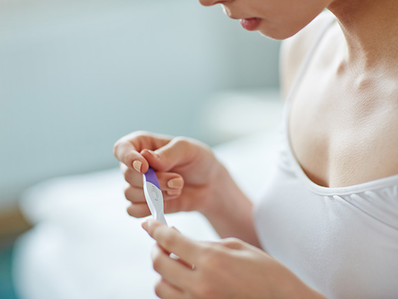 девушка смотрит тест на беременность