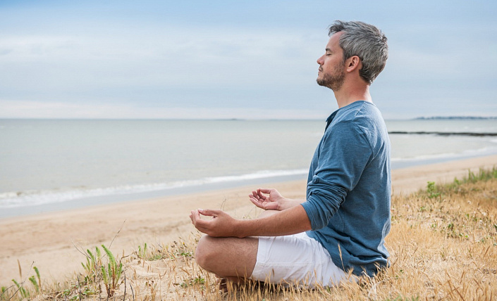 man meditating on the beach