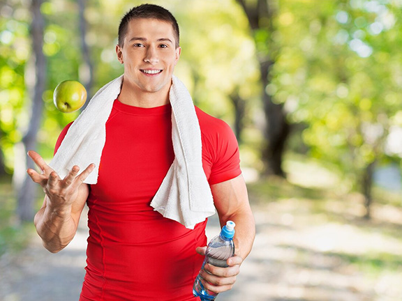 спортивный парень подкидывает яблоко