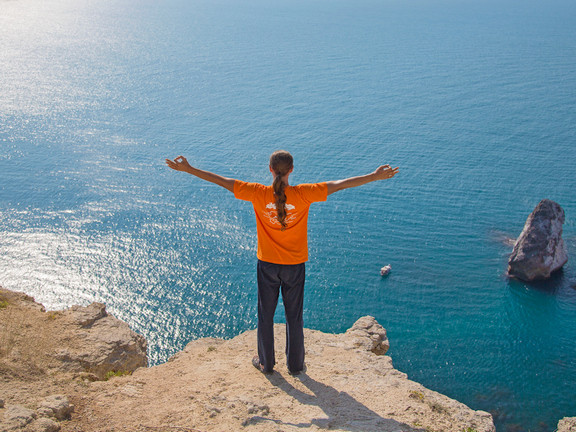 берег моря, мужчна раскинул руки