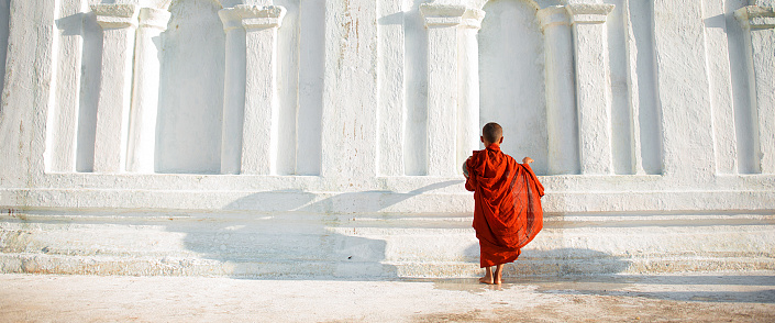мальчик монах на фоне белой стены