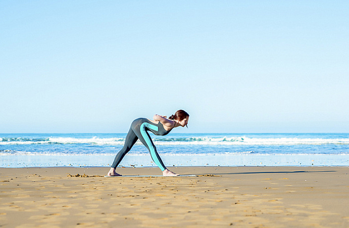 паршвоттанасана, девушка йогиня на берегу моря