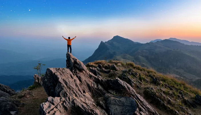 парень на скале поднял руки
