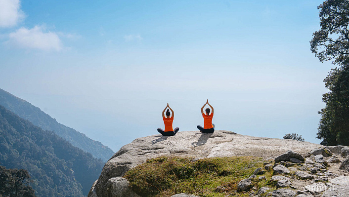 Две девушки в позе лотоса на скале 