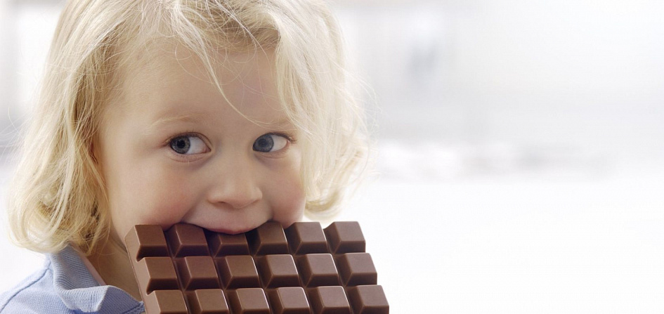 Маленькая девочка кусает шоколадку | 
