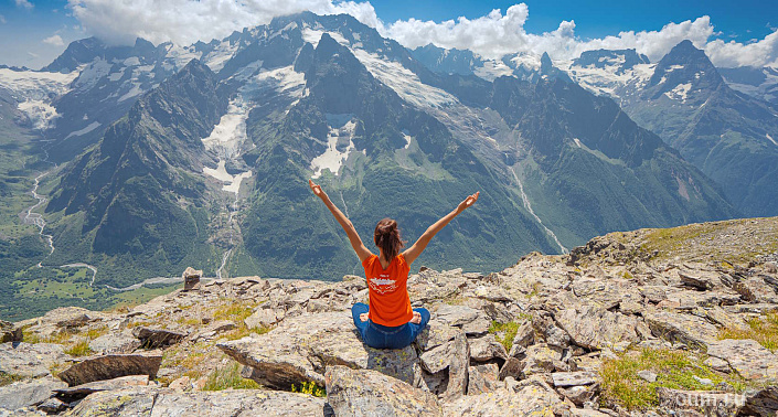Девушка сидит в позе лотоса в горах