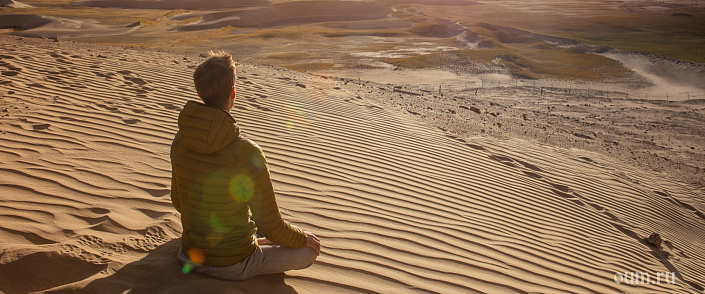парень медитирует на дюнах