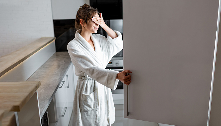 девушка закрывает глаза на холодильник