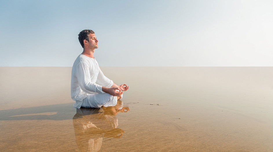 мужчина медитирует на песке