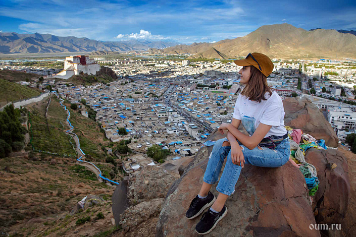 Девушка созерцает, сидя на камне