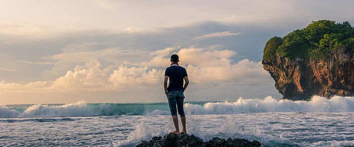 мужчина стоит на камне у моря