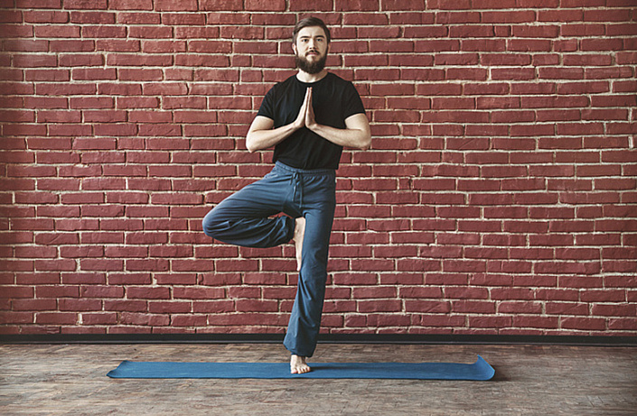 поза дерева, врикшасана, йогин на фоне стены