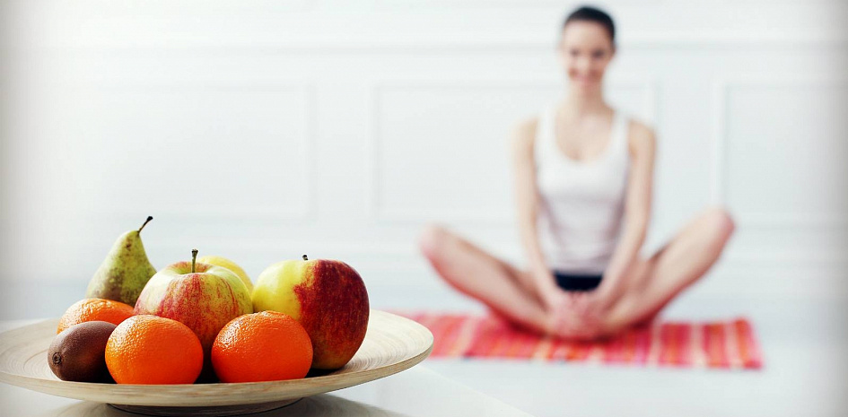 Тарелка с фруктами и девушка в позе йоги |